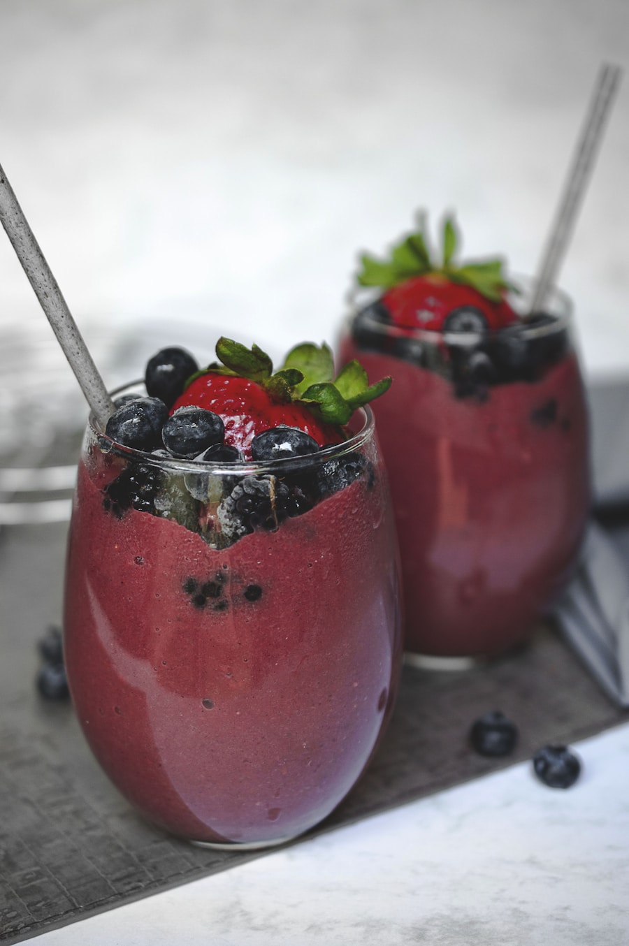 Two tall glasses of chilled strawberry peach smoothie garnished with fresh peach slices and mint